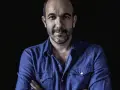 Hombre con barba y camisa vaquera azul, mirada directa. Podría ser DJ Coco listo para pinchar.