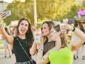Tres amigas con maquillaje festivo y bebidas en un festival de verano.