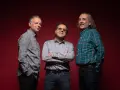 Los miembros de Els Pets posan sonrientes ante un fondo rojo.