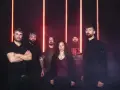 Cinco personas posan ante luces rojas. La banda Otero Brutal Fest lista para un concierto.