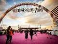 Gente camina bajo un arco con el letrero "When We Were Young Festival" sobre una alfombra rosa.