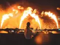 DJ enciende la fiesta en una **nova era beach party** con llamas y una multitud eufórica.