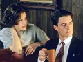 Una mujer y un hombre en una noche sin grabar. Él sostiene una taza de café, ella apoya la cabeza en la mano.