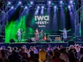 Banda tocando en el iwa fest de Melilla, con luces verdes y moradas, y una multitud disfrutando.