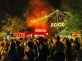 Noche de fiesta con luces de neón "Bertys" y "Food", gente disfrutando, ideal para canciones para un día ewan.