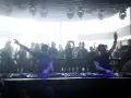 Dos DJs actuando en un club con público al fondo.