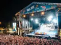 Multitud en concierto, luces brillantes y humo en el escenario. El cartel dice "Love to Rock".