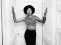 Nikki Hill, con su afro y top de cebra, posa con confianza entre puertas blancas.