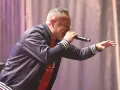 Juan Magán cantando en un escenario con micrófono y gesto animado.
