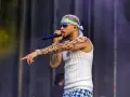 El artista dei v Málaga, con tatuajes y bandana, canta en el escenario.