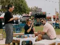 Amigos disfrutan del ambiente de rock en Valencia, con food trucks y música de fondo.