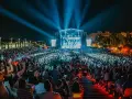 Multitud en un concierto nocturno, luces azules iluminan el escenario y al público. Un evento vibrante, como un **cabaret mairena** moderno.