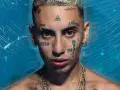 Joven con tatuajes en la cara, incluyendo un ojo dentro de un triángulo, y cadenas de oro. Su estilo neo pistea madrid es inconfundible.