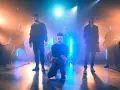 Banda de rock en escenario con luces azules y naranjas, como si estuvieran en un concierto de Linkin Park en Barcelona.