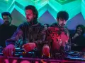 Los agentes del tiempo, DJs concentrados, manipulan las consolas bajo luces de neón, creando ritmos que desafían el tiempo.