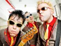Tres músicos con gafas de sol y trajes coloridos, listos para un concierto de mondra roll.