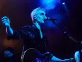Cantante de Belako en concierto, con guitarra y micrófono, bajo luces azules y humo.