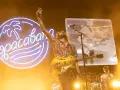 El cantante de Izal en Albacete levanta la mano con su guitarra amarilla, iluminado por un neón de Copacabana.
