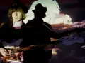 Jacco Gardner, con sombrero y chaqueta, toca el bajo frente a una proyección psicodélica.