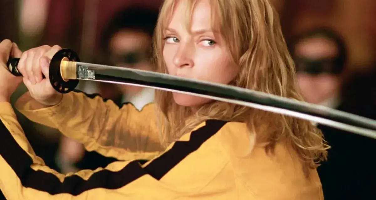La Novia, con su icónico traje amarillo, desenvaina su katana. La banda sonora de Kill Bill resuena en esta escena de acción.