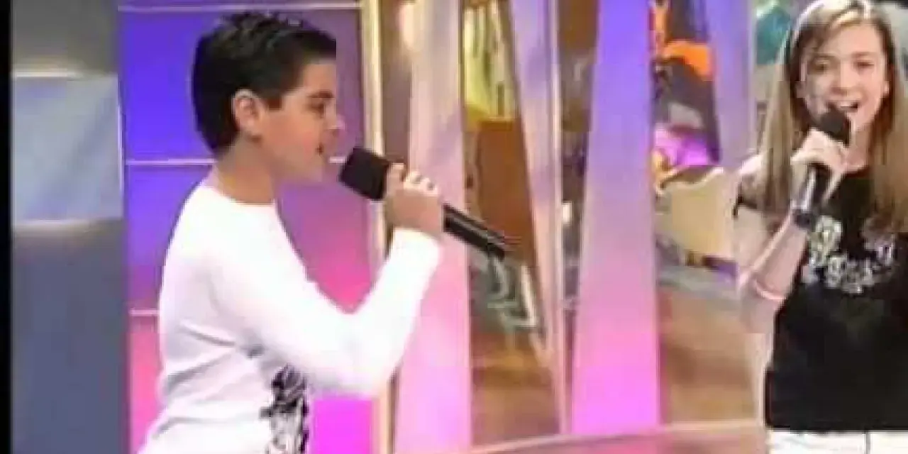 Ana Mena y Abraham Mateo, de niños, cantando con micrófonos en un escenario.