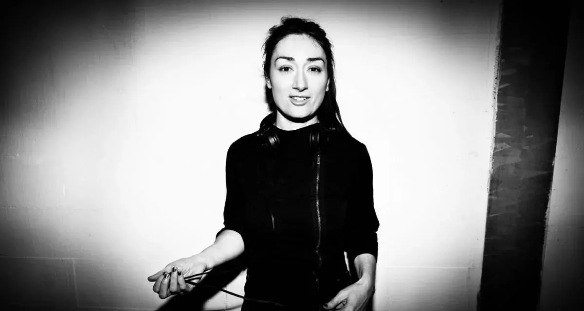 Paula Temple, DJ, con auriculares alrededor del cuello, sostiene cables de audio.