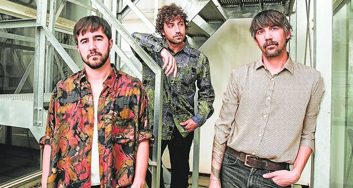Los miembros de Lori Meyers posan juntos, con sus camisas estampadas y miradas serias, listos para su próxima actuación.