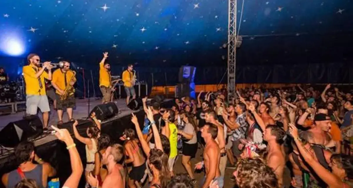 Una banda toca en un escenario ante una multitud animada bajo un techo estrellado.