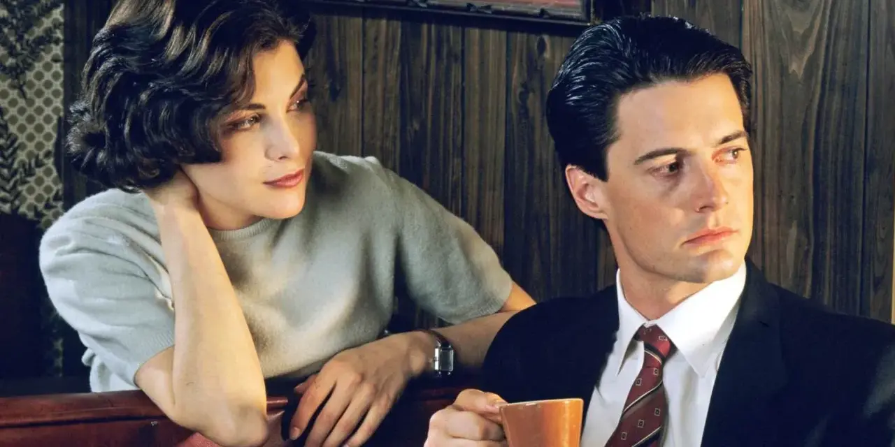 Una mujer y un hombre en una noche sin grabar. Él sostiene una taza de café, ella apoya la cabeza en la mano.