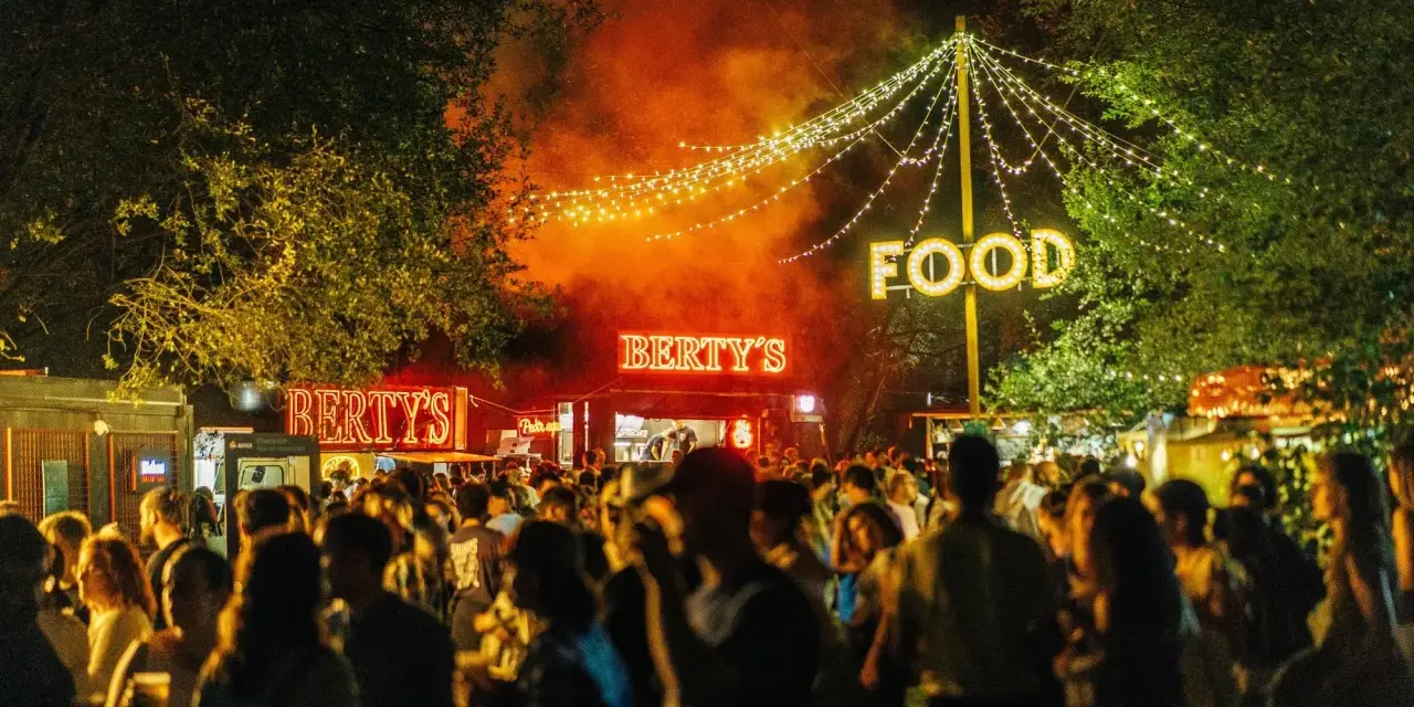 Noche de fiesta con luces de neón "Bertys" y "Food", gente disfrutando, ideal para canciones para un día ewan.