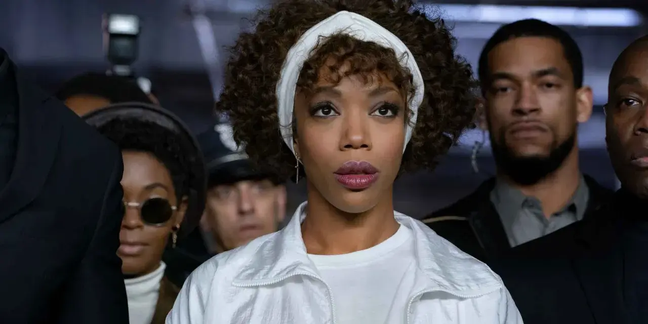 Naomi Ackie como Whitney Houston, lista para cantar "I Wanna Dance with Somebody" rodeada de fans y seguridad.