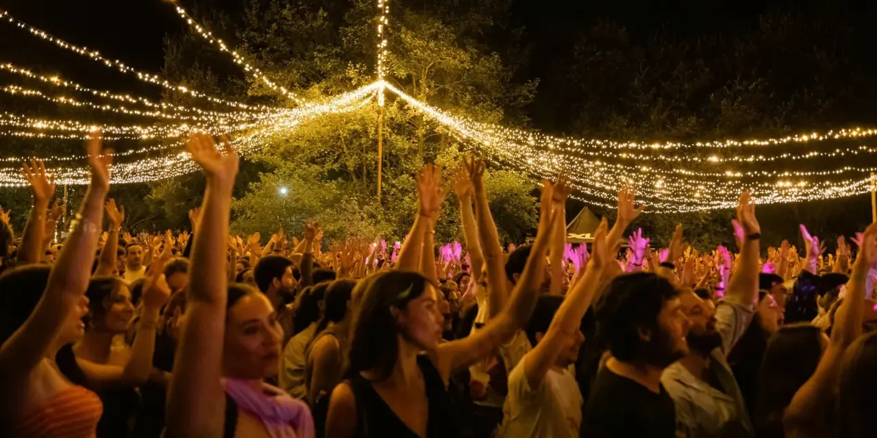 Gente disfrutando en el festival Ewan Salinas bajo un cielo de luces.