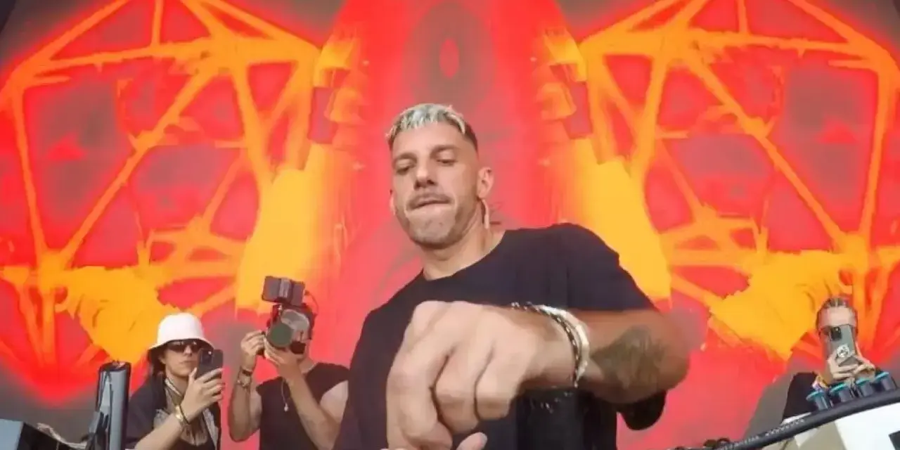 Andrés Campo, DJ, mezcla música en vivo con un fondo psicodélico rojo y naranja.