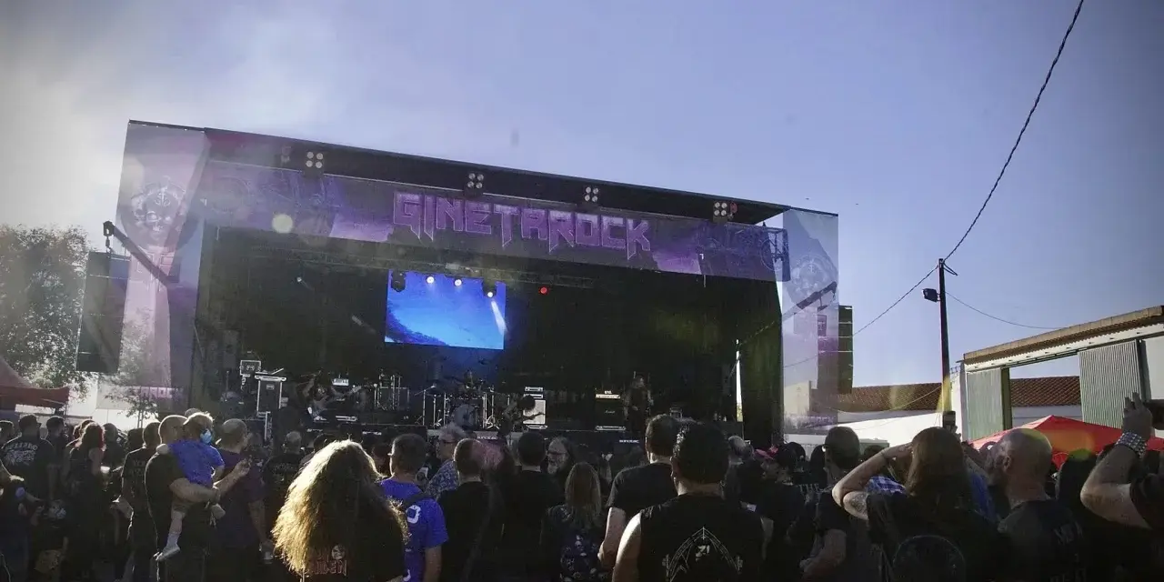 Multitud disfrutando del concierto de gineta rock bajo un cielo azul.