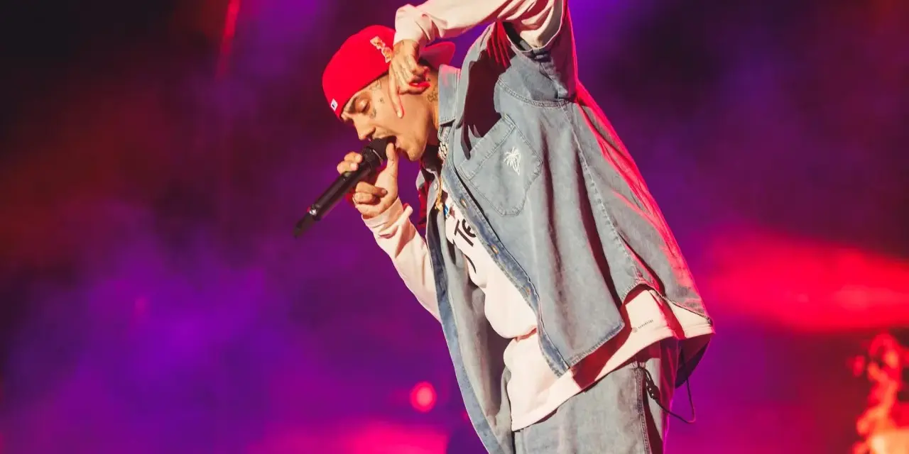 Un artista con gorra roja y ropa vaquera canta en un concierto boombastic Asturias.