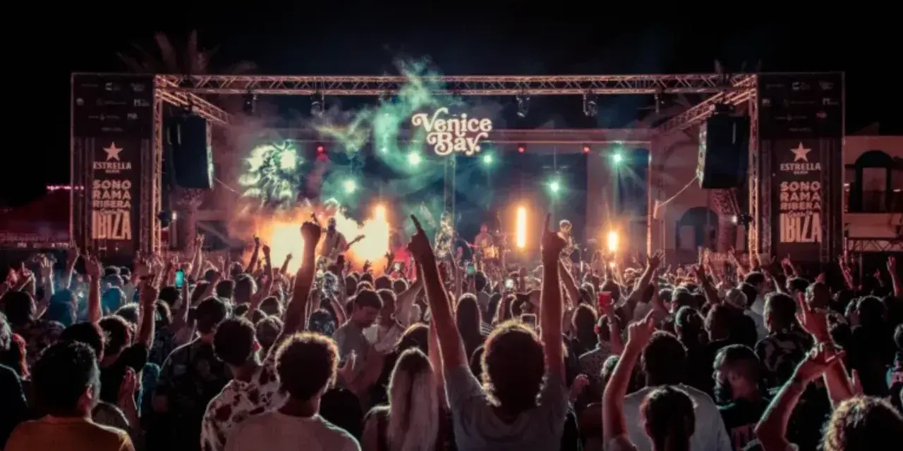 Multitud en concierto bajo luces y humo, con cartel de "Venice Bay" y "Sonorama Ibiza".