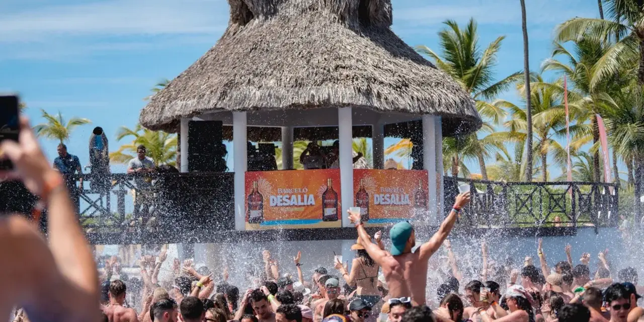 Gente disfrutando en una piscina con un escenario de Barceló Desalia al fondo.