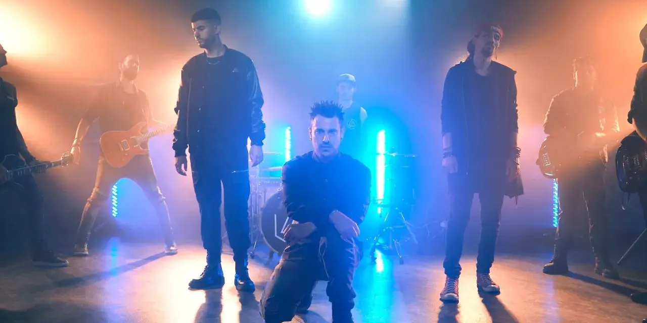 Banda de rock en escenario con luces azules y naranjas, como si estuvieran en un concierto de Linkin Park en Barcelona.