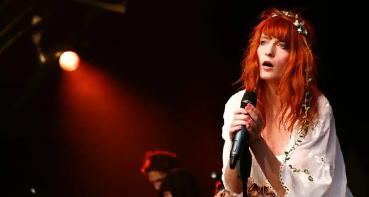 Florence Welch, una de los miembros de Florence and the Machine, canta con pasión en el escenario, iluminada por una luz roja.