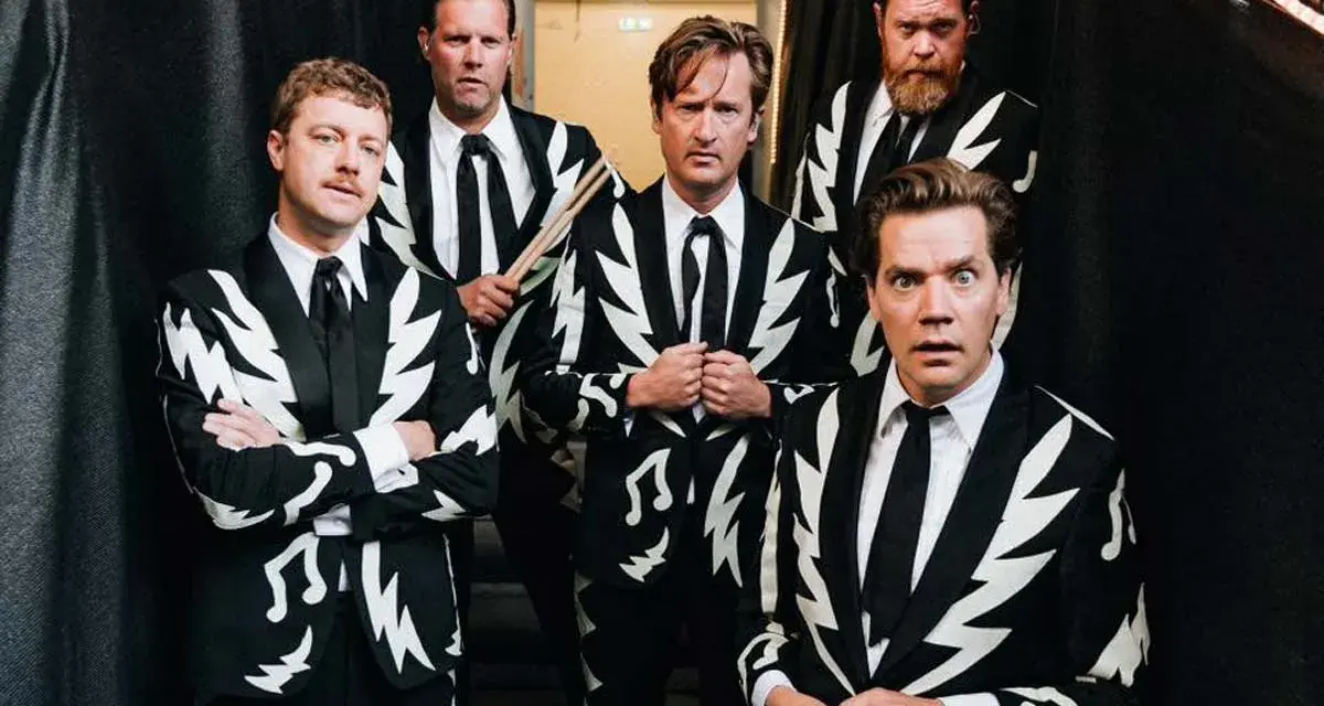 Los miembros de The Hives posan con trajes llamativos. Uno sostiene baquetas, listo para la acción.
