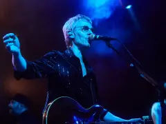 Cantante de Belako en concierto, con guitarra y micrófono, bajo luces azules y humo.