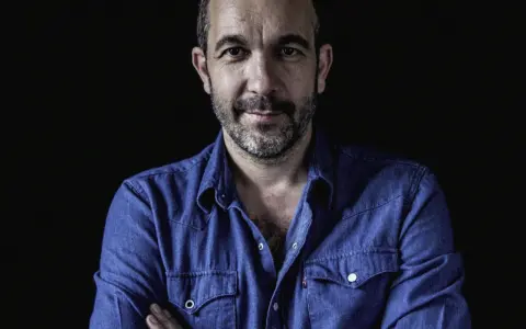 Hombre con barba y camisa vaquera azul, mirada directa. Podría ser DJ Coco listo para pinchar.