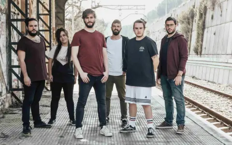 Los miembros de Itaca Band posan en una estación de tren abandonada, listos para su próxima aventura musical.