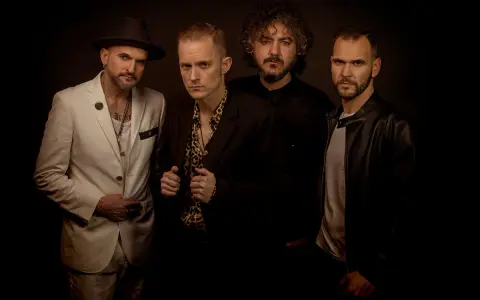 El grupo de embusteros posa con miradas intensas. Uno lleva sombrero y traje blanco, otro camisa de leopardo, y los otros dos, chaquetas oscuras.