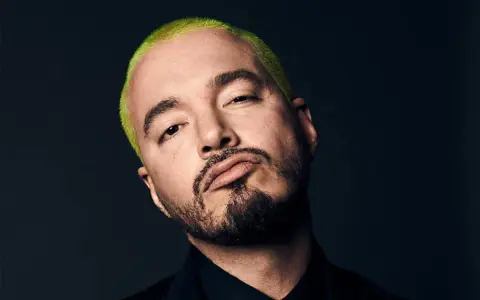 J Balvin, con su característico cabello verde vibrante, posa con una mirada intensa. Podría estar preparándose para un concierto en Madrid.