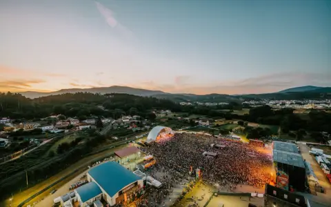 Multitudinaria **rio verbena fest** bajo un atardecer espectacular. Miles de personas disfrutan de la música y el ambiente.