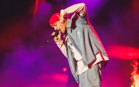 Un artista con gorra roja y ropa vaquera canta en un concierto boombastic Asturias.