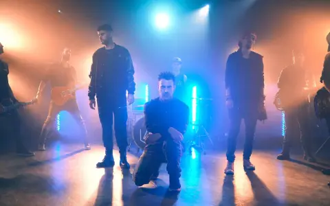 Banda de rock en escenario con luces azules y naranjas, como si estuvieran en un concierto de Linkin Park en Barcelona.