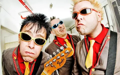 Tres músicos con gafas de sol y trajes coloridos, listos para un concierto de mondra roll.