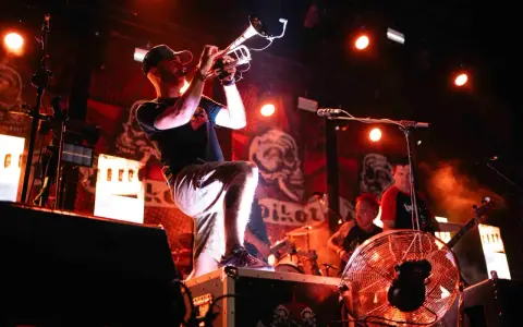 Músico con trompeta en un concierto de soria rock, con luces rojas y fondo de calaveras.